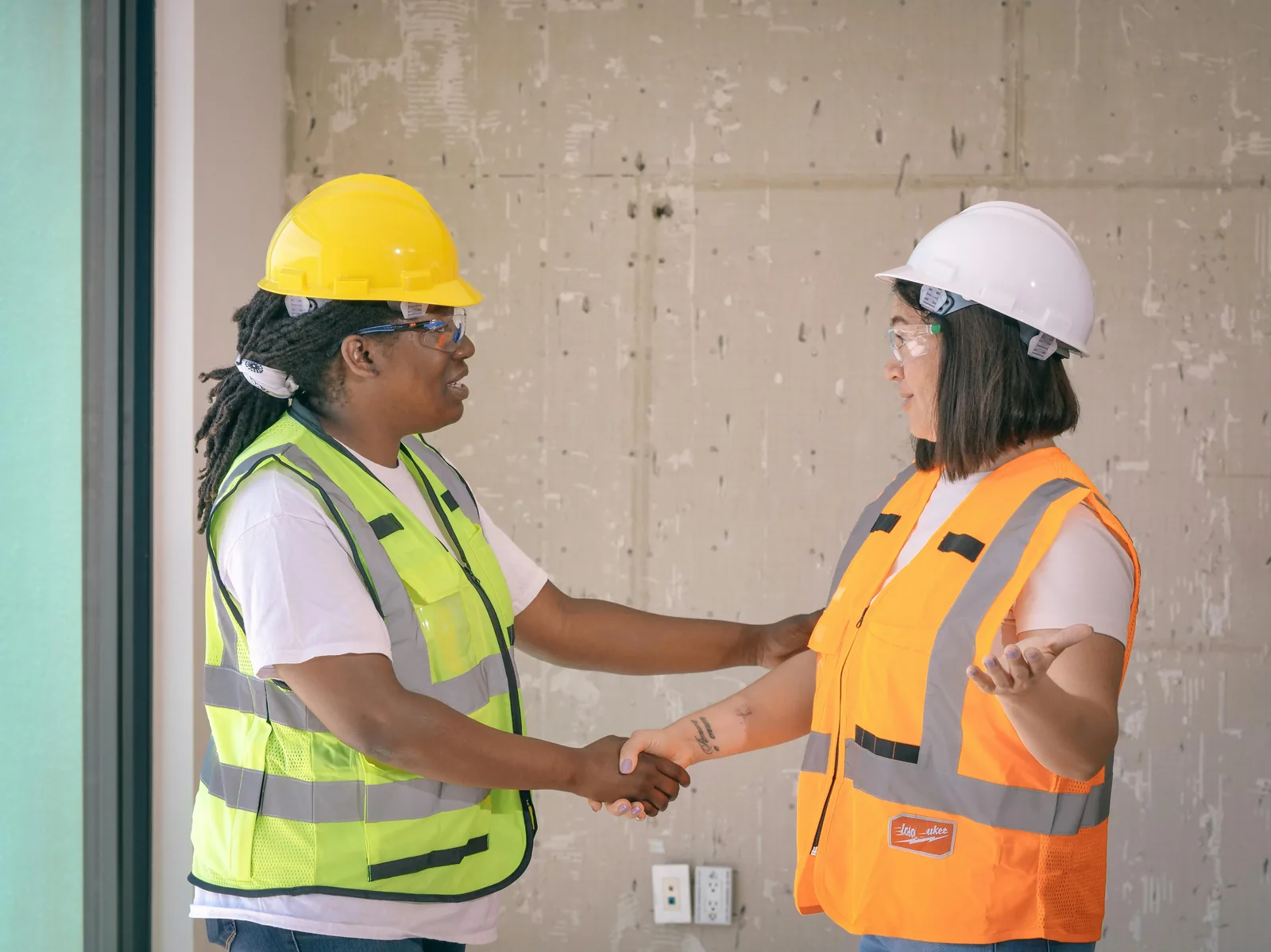 Two business professionals shaking hands in a modern office, the moment of trust customers want to feel when they hire a verified-and-insured service business