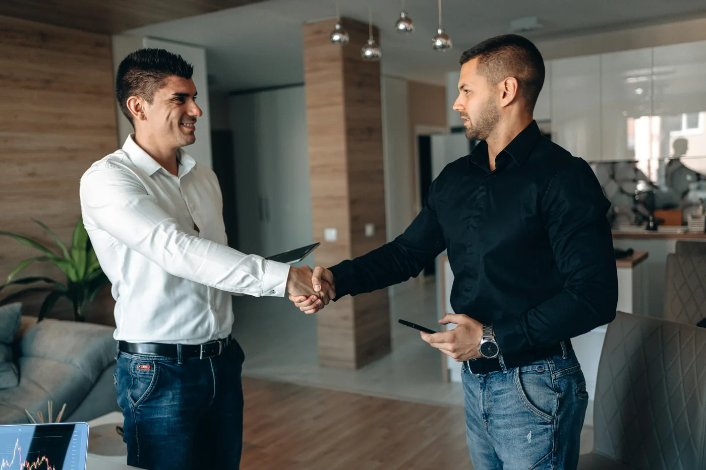 Two field-service workers in hi-vis vests and hard hats shaking hands on the job site, the trade-business audience GBP insurance verification was built for