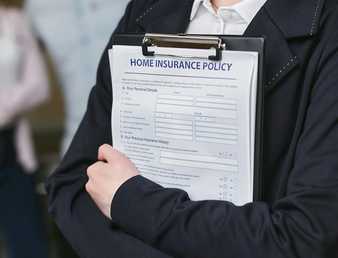 Business owner reviewing a home insurance policy on a clipboard next to a laptop, the kind of pre-upload check that prevents the top rejection reasons